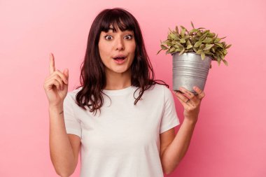 Pembe arka planda izole edilmiş bir bitki tutan beyaz bir kadın. Harika bir fikri var, yaratıcılık kavramı..