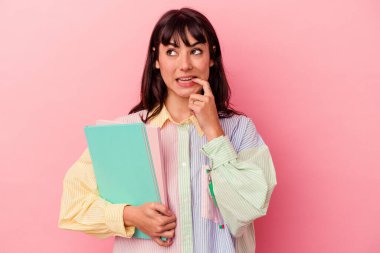 Pembe arka planda izole edilmiş kitaplar tutan beyaz bir kadın. Bir şeyin fotokopi odasına baktığını düşünerek rahatlamış..