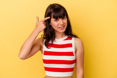 Sarı arka planda izole edilmiş genç beyaz kadın işaret parmağıyla bir hayal kırıklığı gösteriyor..