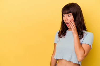 Sarı arka planda izole edilmiş genç beyaz kadın gördüğü bir şey yüzünden şoka uğruyor..