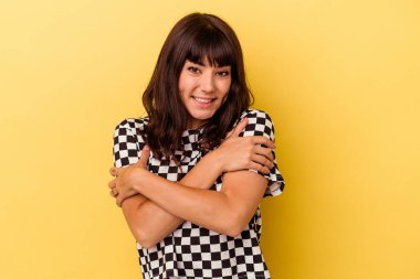 Sarı arka plan kucaklamalarında izole edilmiş, kaygısız ve mutlu bir şekilde gülümseyen beyaz kadın..