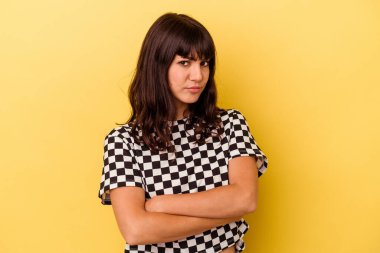 Sarı arka planda izole edilmiş genç beyaz kadın şüpheli, belirsiz, seni muayene ediyor..