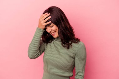 Pembe arka planda izole edilmiş genç beyaz kadın kameraya parmaklarıyla göz kırpıyor, yüzünü kapatmaktan utanıyor..