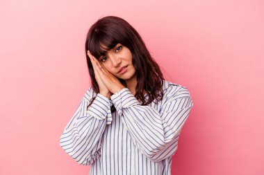 Pembe arka planda izole edilmiş genç beyaz kadın esniyor. Ağzı eliyle kapatan yorgun bir hareket sergiliyor..