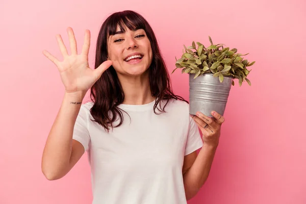 Jonge Kaukasische Vrouw Houden Een Plant Geïsoleerd Roze Achtergrond Glimlachend — Stockfoto