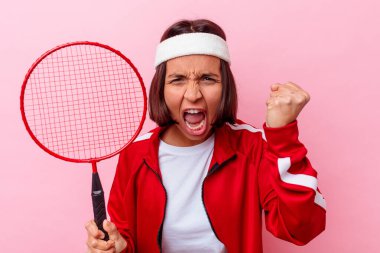 Pembe arka planda soyutlanmış badminton oynayan genç melez kadın.