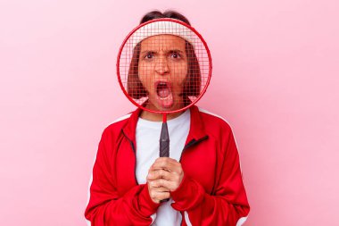 Pembe arka planda soyutlanmış badminton oynayan genç melez kadın.