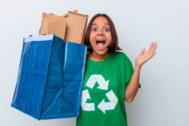 Genç melez kadın, beyaz arka planda izole edilmiş mukavvayı geri dönüştürüyor. Hoş bir sürprizle karşılaşıyor, heyecanlı ve el kaldırıyor..