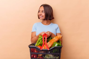 Genç melez kadın bej arka planda alışveriş yapıyor.