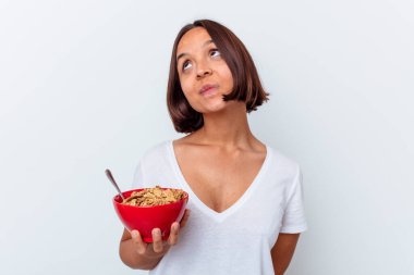 Beyaz arka planda izole edilmiş mısır gevreği yiyen genç bir ırk kadını amaçlarına ve amaçlarına ulaşma hayali kuruyor.