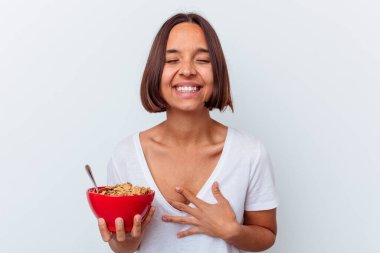 Beyaz arka planda izole edilmiş mısır gevreği yiyen genç bir ırk kadını gülüyor ve eğleniyor..