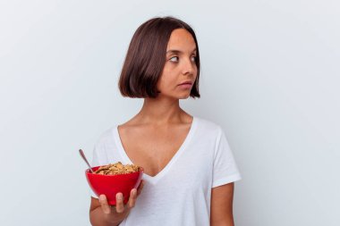 Beyaz arka planda yalıtılmış mısır gevreği yiyen genç bir kadın gülümseyen, neşeli ve keyifli görünüyor..