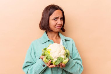 Genç melez kadın elinde bej arka planda izole edilmiş bir lahana tutuyor.