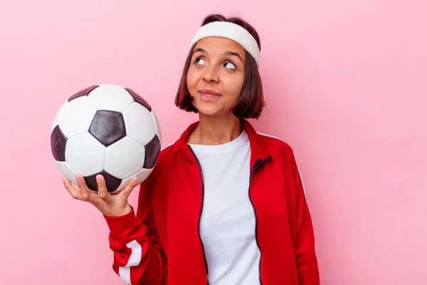 ピンクの背景に孤立したサッカーをしている若い混合人種の女性は 目標と目的を達成することを夢見て — ストック写真