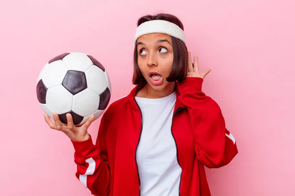若いです混合人種の女性は ピンクの背景に孤立したサッカーをプレイしますゴシップを聞いてみてください — ストック写真