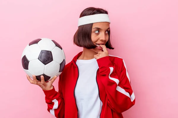 ピンクの背景に孤立したサッカーをしている若い混合人種の女性は コピースペースを見て何かについてリラックスした考え — ストック写真