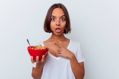 Beyaz arka planda izole edilmiş mısır gevreği yiyen genç bir ırk kadını...