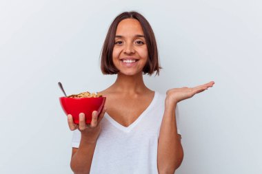 Beyaz arka planda izole edilmiş mısır gevreği yiyen genç bir ırk kadını bir avuç içinde fotokopi alanı ve belinde bir el daha gösteriyor..