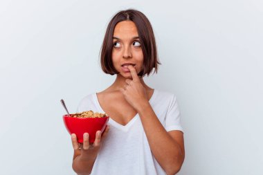 Beyaz arka planda izole edilmiş mısır gevreği yiyen genç bir ırk kadını rahat bir şekilde fotokopi odasına bakan bir şeyi düşünüyor..