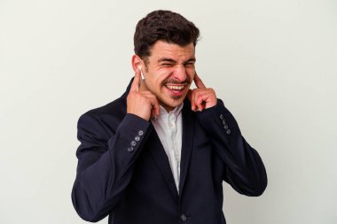 Beyaz arka planda izole edilmiş kablosuz kulaklık takan beyaz iş adamı elleriyle kulaklarını kapatıyor..