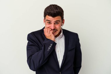 Beyaz arka planda izole edilmiş kablosuz kulaklık takan, tırnak yiyen, gergin ve endişeli genç bir beyaz iş adamı..