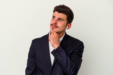 Beyaz arka planda izole edilmiş kablosuz kulaklık takan beyaz iş adamı şüpheli ve şüpheci bir ifadeyle yana bakıyor..