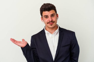 Beyaz arka planda izole edilmiş kablosuz kulaklık takan genç beyaz iş adamı bir avuç içinde fotokopi alanı ve belinde başka bir el tutuyor..