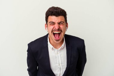 Beyaz arka planda izole edilmiş kablosuz kulaklık takan genç beyaz bir adam çok sinirli ve agresif bağırıyor..