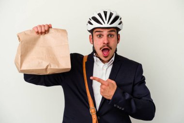 Bisiklet kaskı takan ve elinde tutan genç beyaz arka planda izole edilmiş yiyecekler alan beyaz bir beyaz adam.