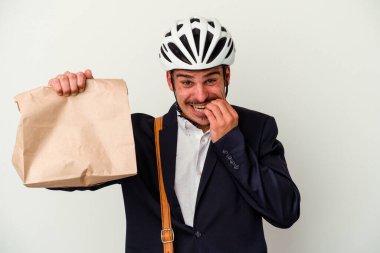 Bisiklet kaskı takan ve elinde tuttuğu genç beyaz arka planda izole edilmiş tırnak yiyen sinirli ve endişeli bir iş adamı..