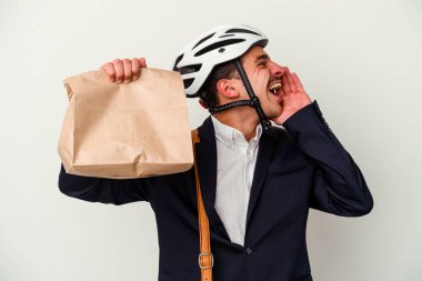 Bisiklet kaskı takan ve elinde tuttuğu genç beyaz atlı adam beyaz arka planda izole edilmiş yiyecekleri alıp avucunu açık tutarak bağırıyor..