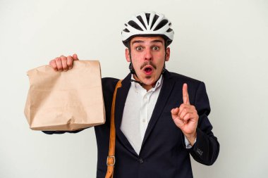 Bisiklet kaskı takan ve elinde tuttuğu genç beyaz arka planda izole edilmiş yiyecekleri alan beyaz bir adam harika bir fikir, yaratıcılık kavramı var..