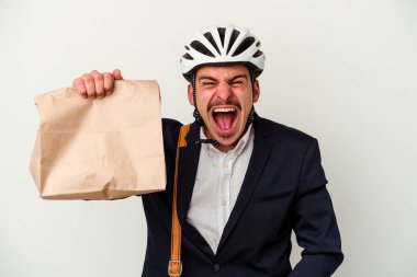 Bisiklet kaskı takan ve elinde tutmakta olan beyaz arka planda izole edilmiş, kızgın ve agresif bir şekilde bağıran genç beyaz iş adamı..