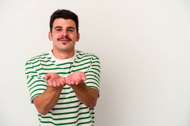 Beyaz arka planda izole edilmiş genç beyaz bir adam dudaklarını katlıyor ve hava öpücüğü vermek için avuç içleri tutuyor..