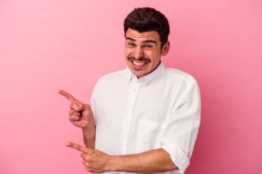 Pembe arka planda izole edilmiş genç beyaz adam işaret parmağıyla fotokopi alanını işaret ederek şok oldu..