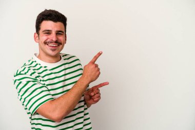 Beyaz arka planda izole edilmiş genç beyaz bir adam işaret parmağıyla fotokopi alanını işaret ederek heyecan ve arzusunu ifade ediyor..