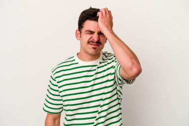 Beyaz arka planda izole edilmiş genç beyaz bir adam bir şeyi unutuyor. Alnına avuç içi ve gözlerini kapayarak vuruyor..