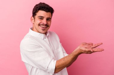 Pembe arka planda izole edilmiş beyaz bir adam elinde bir fotokopi odası tutuyor..