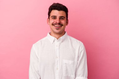 Pembe arka planda izole edilmiş genç beyaz adam mutlu, güler yüzlü ve neşeli.