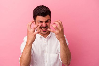 Pembe arka planda izole edilmiş genç beyaz adam gergin elleriyle çığlık atıyor..