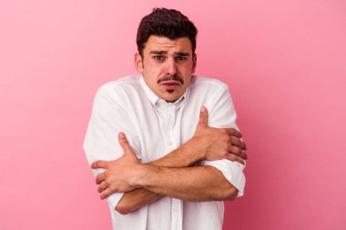 Pembe arka planda izole genç beyaz adam düşük ateş ya da hastalık yüzünden soğuyor..