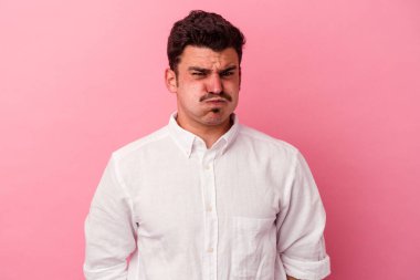 Pembe arka planda izole edilmiş genç beyaz adamın yanakları şişer, yorgun bir ifadesi vardır. Yüz ifadesi kavramı.