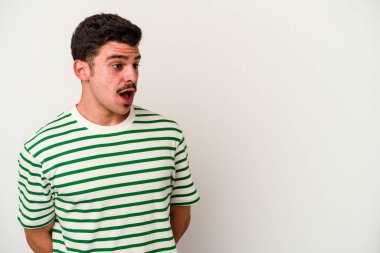 Beyaz arka planda izole edilmiş genç beyaz adam gördüğü bir şey yüzünden şoka uğruyor..