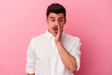 Pembe arka planda izole edilmiş genç beyaz adam gizli bir sıcak fren haberi veriyor ve yana bakıyor.