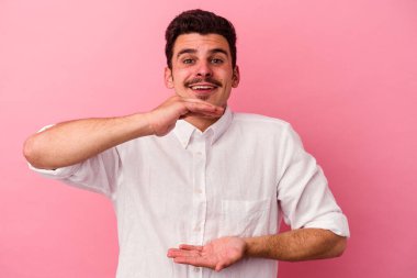 Pembe arka planda izole edilmiş beyaz bir adam iki eliyle bir şey tutuyor, ürün sunumu..