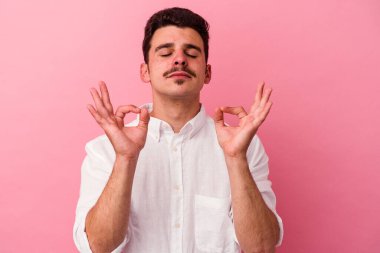 Pembe arka planda izole edilmiş genç beyaz adam sıkı çalışma gününden sonra rahatlıyor. Yoga yapıyor..