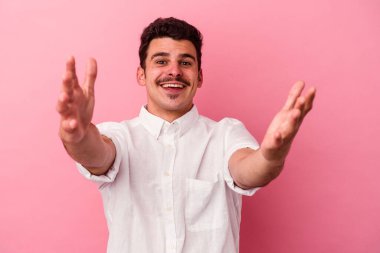 Pembe arka planda izole edilmiş genç beyaz adam kameraya sarıldığı için kendinden emin hissediyor..