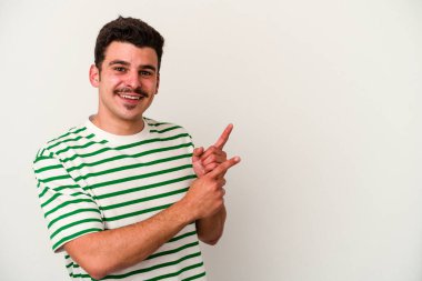 Beyaz arka planda izole edilmiş genç beyaz bir adam işaret parmağıyla fotokopi alanını işaret ederek şok oldu..