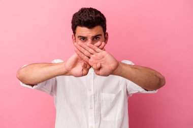 Pembe arka planda izole edilmiş genç beyaz adam inkar jesti yapıyor.