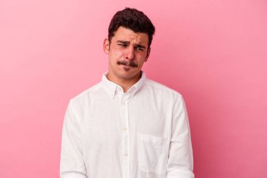 Pembe arka planda soyutlanmış, kafası karışmış, şüpheli ve kararsız genç bir beyaz adam..